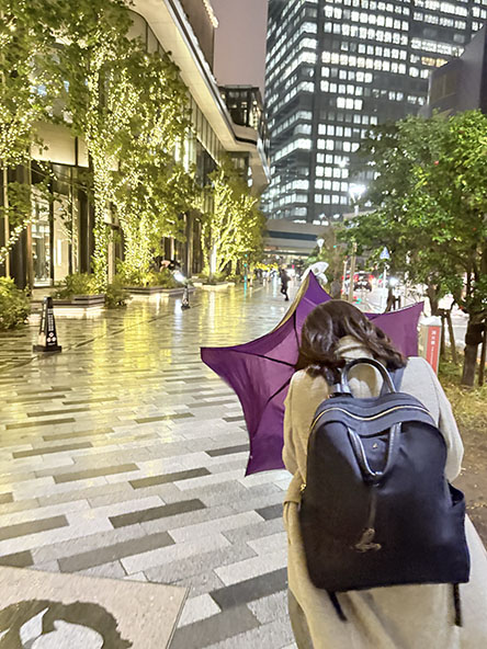 風で傘がたわんどる